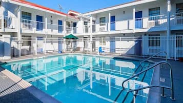 A hotel with a swimming pool, multiple balconies, and a red-tiled roof.