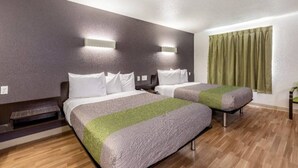 Une chambre d’hôtel avec deux lits, un plancher en bois et une fenêtre avec des rideaux.