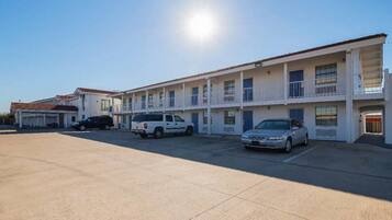 A motel with multiple rooms, a parking lot, and a clear sky.