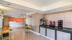 A hotel lobby with a reception desk, chairs, and a tiled floor. - 2 FULL BEDS | SMOKING (Grand Prairie)