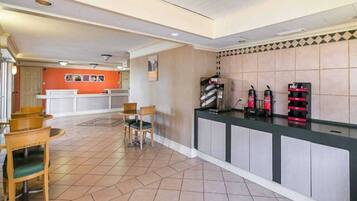 A hotel lobby with a reception desk, chairs, and a tiled floor.