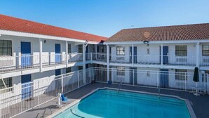 A hotel with a swimming pool, multiple balconies, and a red-tiled roof. - 2 FULL BEDS | SMOKING (Grand Prairie)