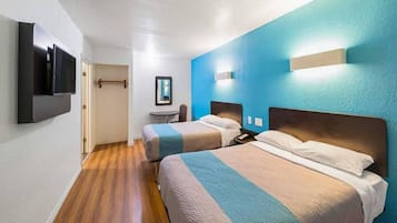 Habitación de hotel con dos camas, un televisor de pantalla plana, una mesita y un espejo.