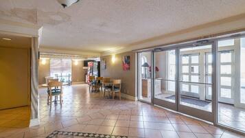 A spacious living area with a tiled floor, a dining table with chairs, and a large sliding glass door leading to an outdoor area.