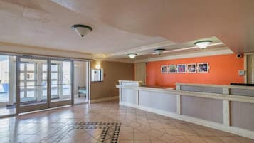 A reception area with a check-in counter, a patterned floor, and a door leading outside.