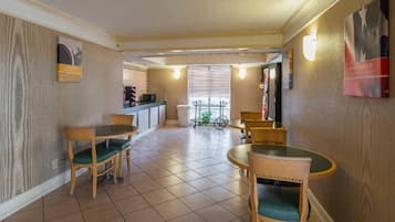 A dining area with a kitchen in the background, a bicycle, and a trash can.