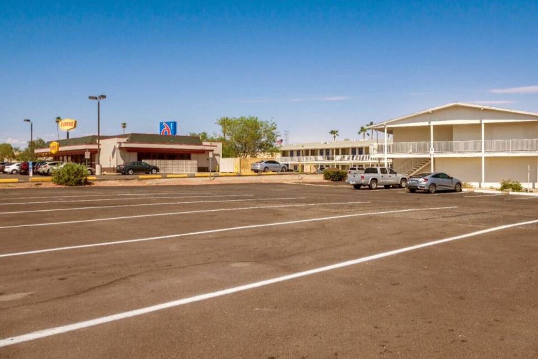 A parking lot with a motel and a gas station in the background.