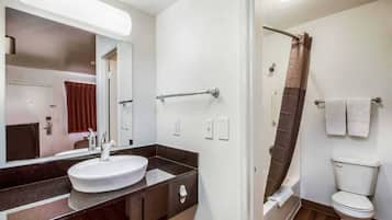 A bathroom with a sink, mirror, towel rack, shower curtain, and toilet.