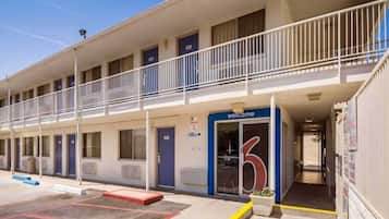 Ein Motel mit einem blauen 'Welcome'-Schild, einem Empfangsgebäude und einem Parkplatz.