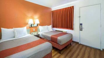 A hotel room with two beds, a nightstand, a lamp, a window with curtains, and a door.