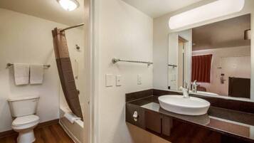 A bathroom with a toilet, shower, and sink.