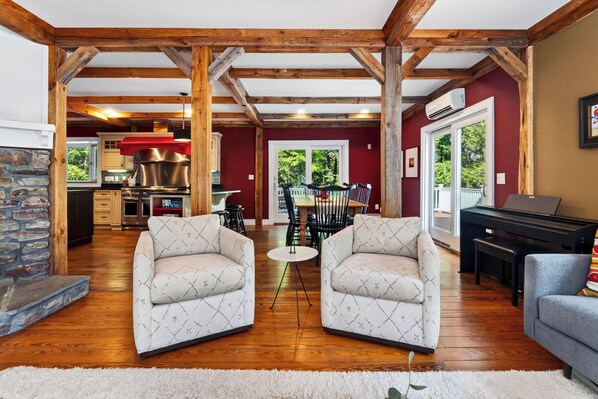 A spacious living area with a fireplace, a dining table with chairs, and a piano.