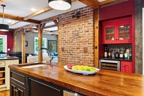 A kitchen with a wooden island, red cabinets, and a brick wall.