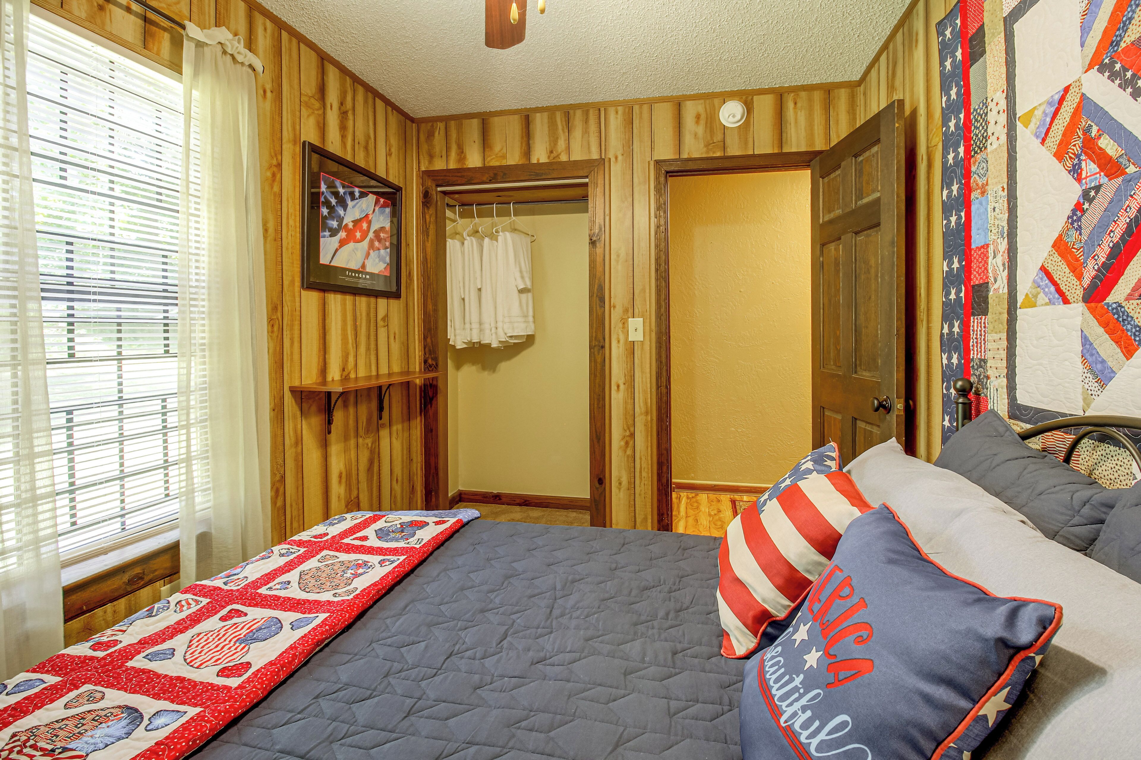 Ein Schlafzimmer mit einem Bett, Kissen, einer Tagesdecke, einem Fenster mit Jalousien, einer Tür und einer Wand mit einer Decke.