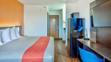 A hotel room with a bed, a desk, a chair, and a television.