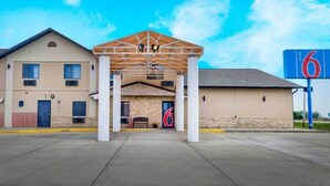 A motel with a covered entrance, a large '6' sign, and a parking lot. - 2 Queen Beds | Non-Smoking, Mini Fridge (Percival)