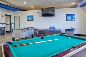 A pool table with a foosball table and seating area in a room with a flat-screen TV mounted on the wall. - 2 Queen Beds | Non-Smoking, Mini Fridge (Percival)