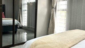 A hotel room with a bed, a sliding glass door, and a view of another room.