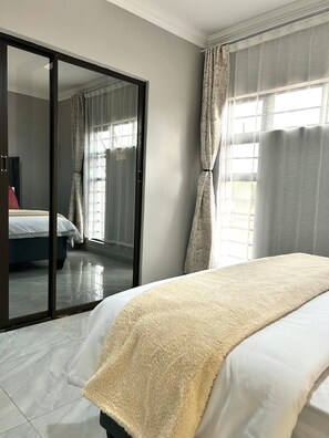A hotel room with a bed, a sliding glass door, and a view of another room.