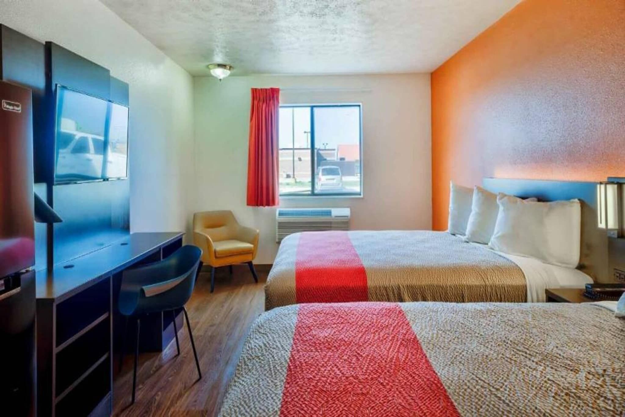 Ein Hotelzimmer mit Bett, Schreibtisch, Stuhl, Fernseher und Fenster.