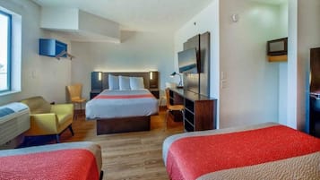 A hotel room with two beds, a desk, a chair, a TV, and a window.