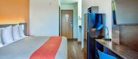 A hotel room with a bed, a desk, a chair, and a television.