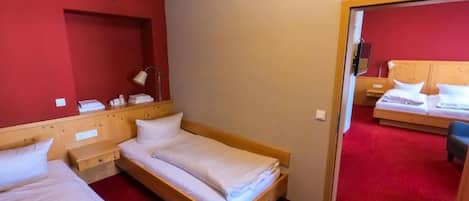 A hotel room with two beds, a red carpet, and a wooden headboard.