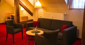 Una sala de estar acogedora con sofá, dos sillones, una mesita de centro y una lámpara.