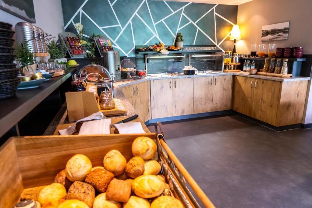 Zona de desayuno tipo buffet con diversas opciones de comida y una caja de madera llena de pasteles.