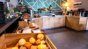 Zona de desayuno tipo buffet con diversas opciones de comida y una caja de madera llena de pasteles.