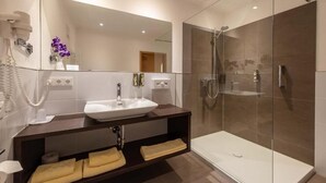 A modern bathroom with a glass-enclosed shower, a white sink, and a dark wooden vanity.