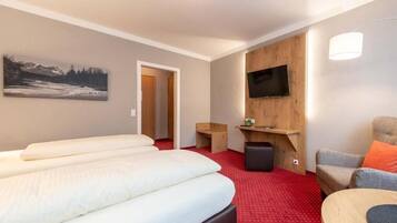 Habitación de hotel con cama, televisión montada en la pared, una mesita y una silla.