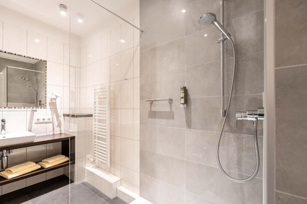 A modern bathroom with a glass shower enclosure, a vanity with a mirror, and a towel rack.