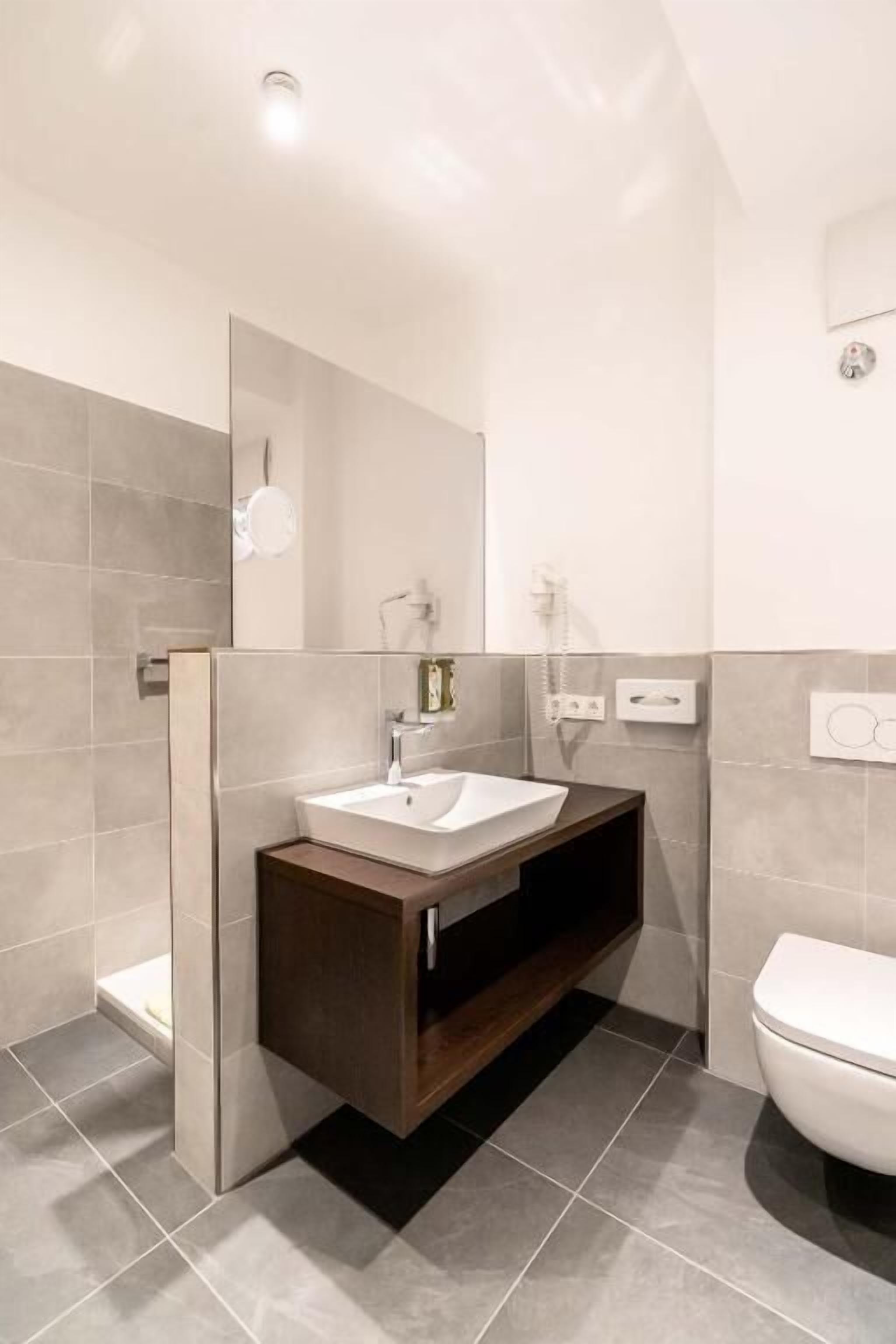 Ein modernes Badezimmer mit Waschtisch, Spüle, Spiegel und Toilette.