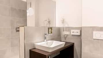 Ein modernes Badezimmer mit Waschtisch, Spüle, Spiegel und Toilette.
