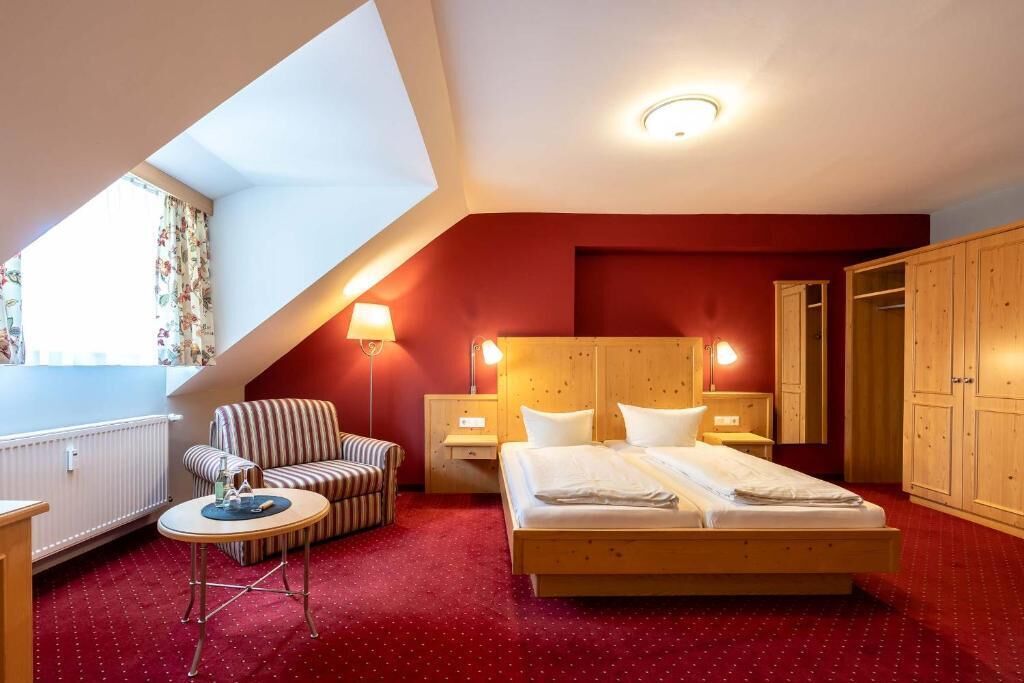 Une chambre à coucher avec un lit, une chaise, une petite table et une armoire.