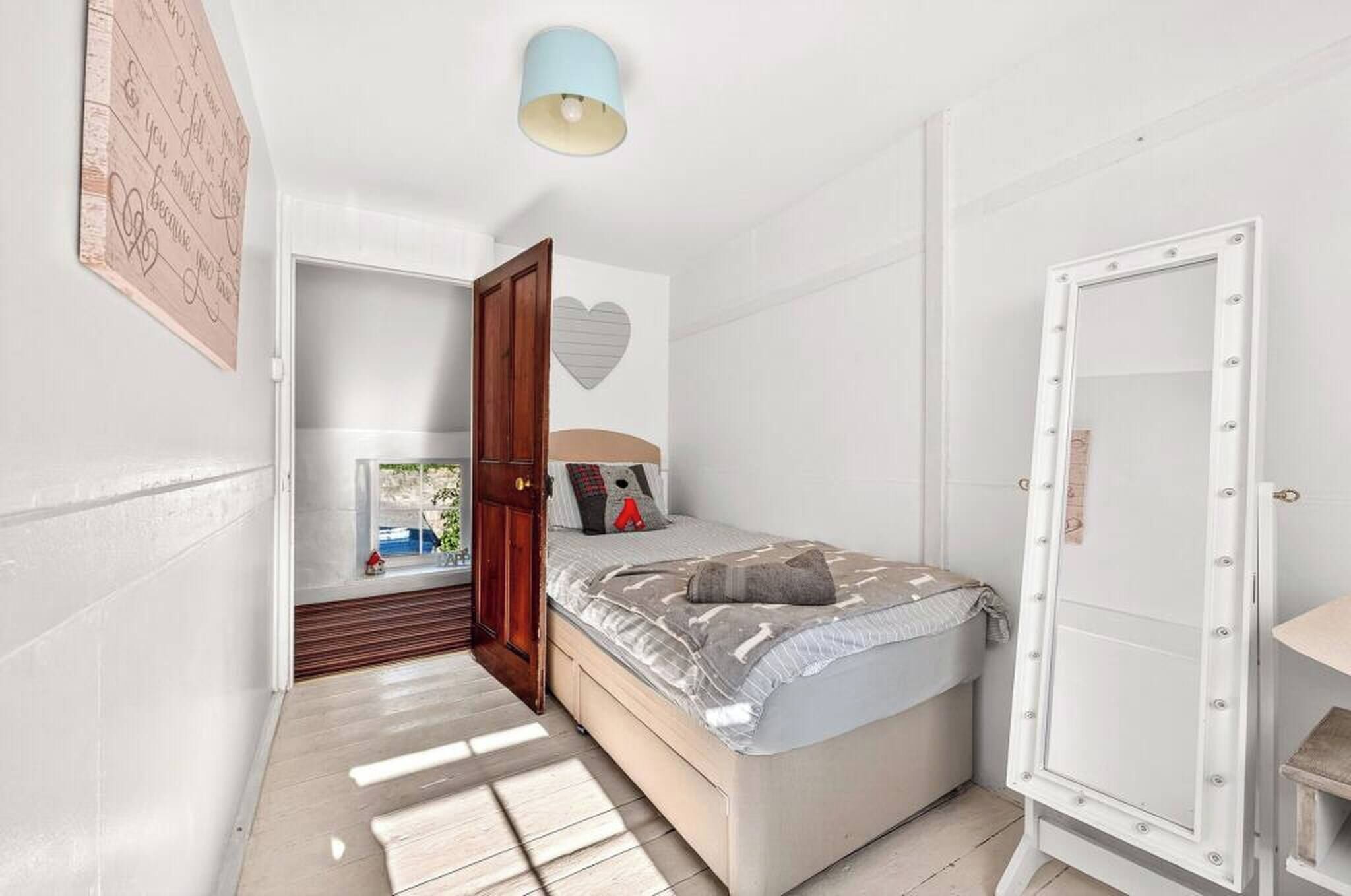 A bedroom with a bed, a wardrobe, a door, and a ceiling light.