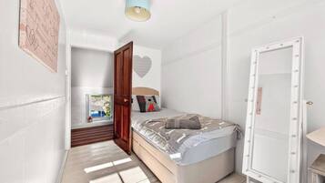 A bedroom with a bed, a wardrobe, a door, and a ceiling light.