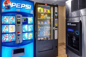 Una macchina distributrice con il logo Pepsi, una varietà di snack e un distributore di Coca-Cola.