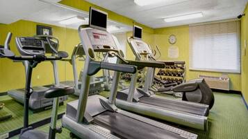 A gym with treadmills, a stationary bike, and a set of dumbbells.