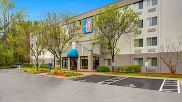 Ein Hotel mit Parkplatz, einer blauen Markise und einem Schild mit dem Logo '6'.