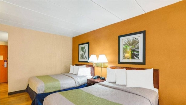 Ein Hotelzimmer mit zwei Betten, Holzboden und zwei Wandlampen.