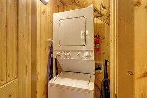 A compact, white, stacked washer and dryer unit in a wooden room. - Woolly Bugger Cabin: Hot Tub & Fishing Pond (Blue Ridge)