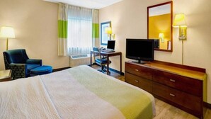 Ein Hotelzimmer mit einem Bett, einem Schreibtisch mit Computer, einem Fernseher und einem Sessel.
