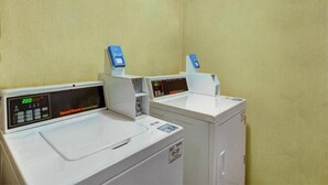 Eine Wäscherei mit zwei Waschmaschinen und Trocknern, alle mit digitalen Anzeigen und Bedienfeldern.