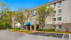 Ein Hotel mit Parkplatz, einer blauen Markise und einem Schild mit dem Logo '6'.