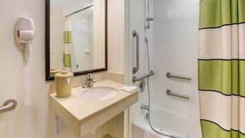 Ein Badezimmer mit Waschbecken, Spiegel, Handtuchhalter und Dusche mit Haltegriffen.