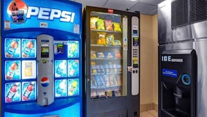 Ein Getränkeautomat mit Pepsi-Logo, einer Auswahl an Snacks und einem Coca-Cola-Spender.