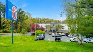 Ein Motel mit Parkplatz, ein Gebäude mit einem Schild und Bäume im Hintergrund.