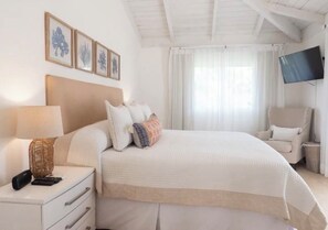 A hotel room with a bed, bedside table, lamp, chair, TV, and framed artwork on the wall. - Luxurious 4-Bedroom Villa with Private Pool in La Romana (La Romana city)